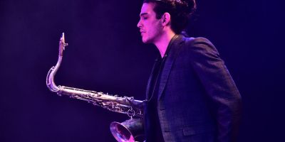 Mattia Basilico, giovane sassofonista jazz italiano, durante un'esibizione dal vivo illuminata da luci di scena viola e blu, protagonista del Monfrà Jazz Fest 2026.