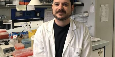 Il ricercatore Enrico Milan nel laboratorio del Dipartimento di Biologia dell'Università di Padova, circondato da strumenti e materiali utilizzati per la ricerca biomedica sul mieloma multiplo.
