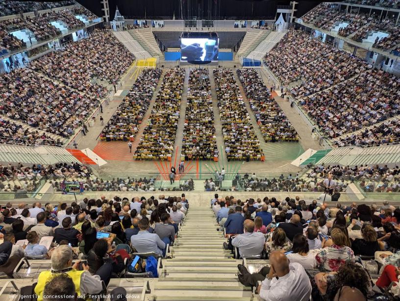 Vista panoramica dell’Inalpi Arena di Torino gremita di partecipanti durante un congresso dei Testimoni di Geova, con migliaia di persone sedute sugli spalti e nell’area centrale dell’impianto.