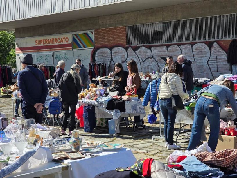 Visitatori ed espositori al Mercatino del Vintage del Quartiere Cristo di Alessandria tra oggetti da collezione, abbigliamento usato e curiosità del passato.