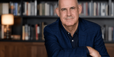 Ritratto fotografico realistico dello scrittore Harlan Coben in un ambiente elegante circondato da libri, con espressione riflessiva e atmosfera culturale.