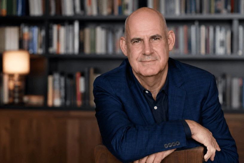 Ritratto fotografico realistico dello scrittore Harlan Coben in un ambiente elegante circondato da libri, con espressione riflessiva e atmosfera culturale.