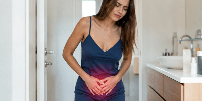 Donna che avverte dolore al basso ventre in un bagno domestico. Immagine fotografica realistica che rappresenta i sintomi tipici di un'infezione delle vie urinarie.