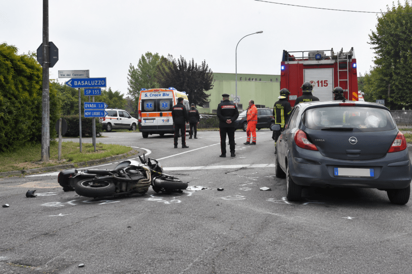 Incidente stradale tra auto e moto a un incrocio di una strada provinciale, con la presenza di mezzi di soccorso, Carabinieri e Vigili del Fuoco intervenuti sul luogo della tragedia.
