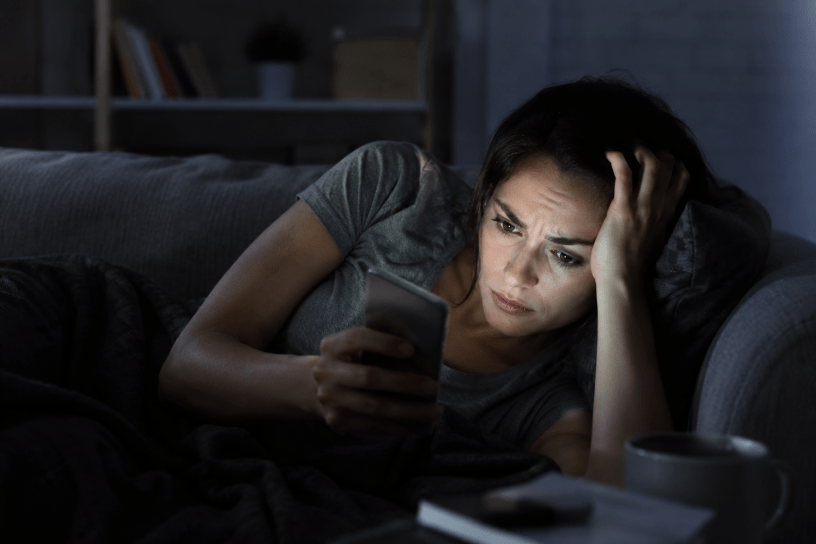 Persona che legge notizie sullo smartphone durante la notte con espressione preoccupata, simbolo dell'ansia informativa e del fenomeno del doomscrolling.