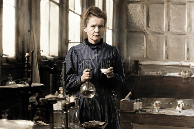 Ritratto realistico di Marie Curie nel suo laboratorio storico mentre osserva strumenti scientifici tra provette e apparecchiature utilizzate per gli studi sulla radioattività.