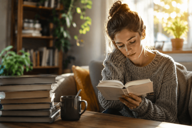 Persona che legge un libro in un ambiente luminoso e tranquillo.