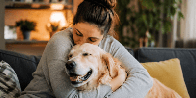 Donna che abbraccia affettuosamente il proprio cane sul divano di casa, in un ambiente accogliente e rilassante, simbolo del legame emotivo tra esseri umani e animali domestici.