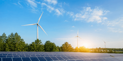 Impianto di energia rinnovabile con pannelli fotovoltaici e turbine eoliche immersi in un paesaggio naturale al tramonto, simbolo della transizione energetica sostenibile.