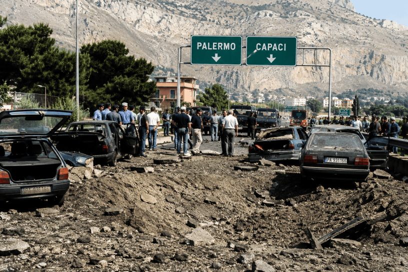 Ricostruzione fotografica della strage di Capaci con l'autostrada devastata dall'esplosione, veicoli coinvolti nell'attentato e forze dell'ordine sul luogo della tragedia che costò la vita a Giovanni Falcone, Francesca Morvillo e agli agenti della scorta.