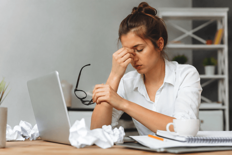 Donna visibilmente stanca davanti al computer in un ufficio domestico, simbolo dello stress quotidiano, della mancanza di sonno e dell'affaticamento mentale.
