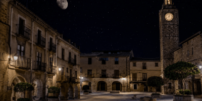 Piazza antica illuminata dalla luna in una notte estiva, con edifici storici, torre dell'orologio e atmosfera silenziosa e suggestiva ispirata alla poesia Notte d'estate di Antonio Machado.