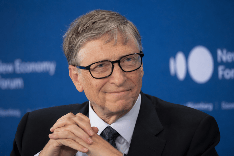 Bill Gates durante un evento internazionale dedicato all'innovazione e al futuro, ritratto in un'immagine realistica che richiama i temi della tecnologia, della salute globale e del progresso scientifico.