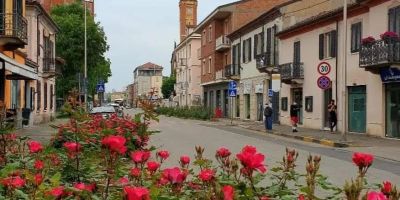 Veduta di Corso Acqui nel Quartiere Cristo di Alessandria, con aiuole fiorite in primo piano, edifici storici, attività commerciali e una delle principali arterie della zona sud della città.