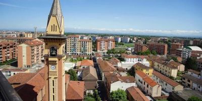 Panorama aereo del Quartiere Cristo di Alessandria con il campanile della chiesa, edifici residenziali, strade e vista sulla città in una giornata di sole.