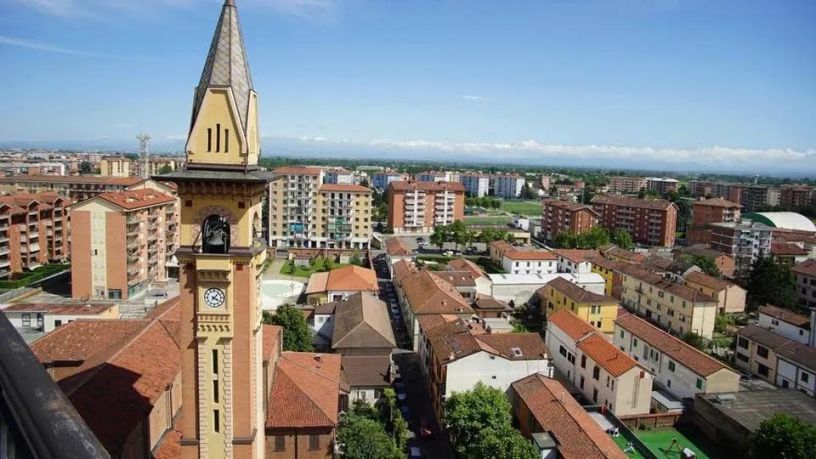 Panorama aereo del Quartiere Cristo di Alessandria con il campanile della chiesa, edifici residenziali, strade e vista sulla città in una giornata di sole.