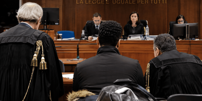 Aula di tribunale durante un processo di grande rilevanza mediatica, con giudici, avvocati e imputato presenti durante la lettura della sentenza.