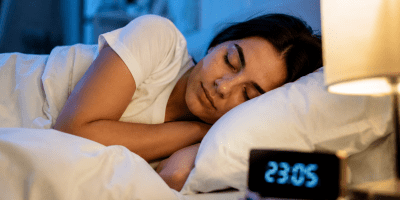 Donna che dorme serenamente nel proprio letto durante la notte, simbolo di riposo, benessere e qualità del sonno.