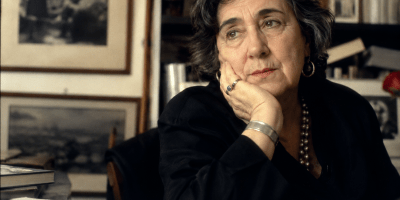 Ritratto fotografico ispirato ad Alda Merini, immersa in un ambiente raccolto tra libri, ricordi e luce soffusa, simbolo della libertà dei sogni e della forza della poesia.