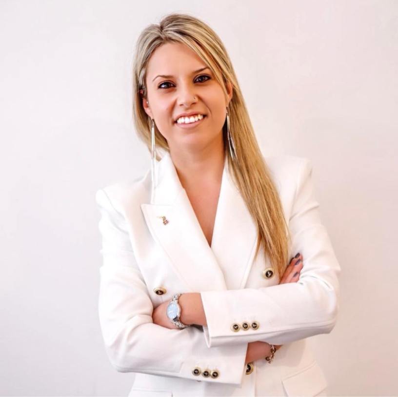 Ritratto di Laura Adduce, Capogruppo della Lega in Consiglio Comunale a Rivoli, in posa con giacca bianca e braccia incrociate.