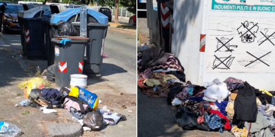 Rifiuti e indumenti abbandonati accanto ai cassonetti della raccolta differenziata e al contenitore per gli abiti usati in una strada di Alessandria. Le immagini mostrano sacchi, vestiti e materiali vari lasciati sul marciapiede, con evidenti problemi di decoro urbano.