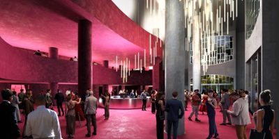 Render del nuovo foyer del Teatro Comunale di Alessandria con ampi spazi interni moderni, illuminazione artistica sospesa, colonne monumentali e visitatori durante un evento culturale. Il progetto mostra l'aspetto previsto della struttura dopo la riqualificazione.