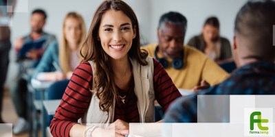 Partecipanti a un corso di formazione professionale in aula durante una lezione. In primo piano una giovane donna sorridente segue l’attività didattica, simbolo delle opportunità offerte dai voucher formativi per la crescita professionale