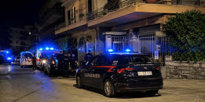 Carabinieri e mezzi di soccorso davanti a un condominio di Sanremo durante le indagini per l'omicidio di una donna trovata morta nella sua abitazione.