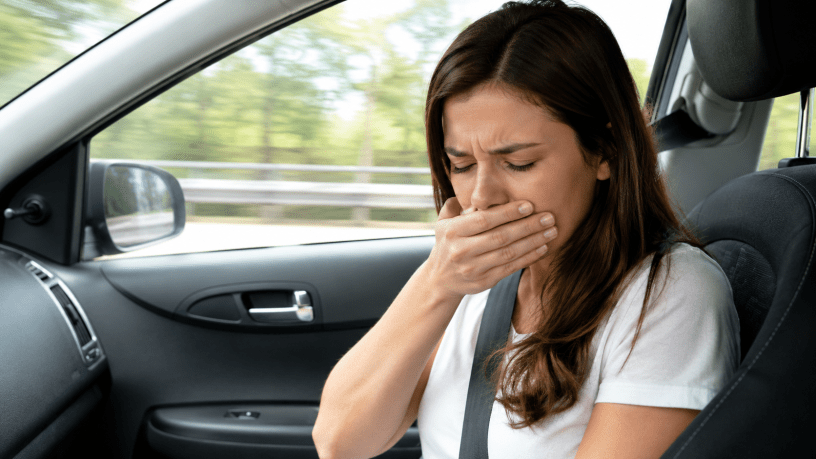 Persona seduta sul sedile del passeggero che manifesta sintomi di mal d'auto durante un viaggio, con espressione di nausea, a rappresentare la cinetosi e il conflitto tra cervello e sistema vestibolare.
