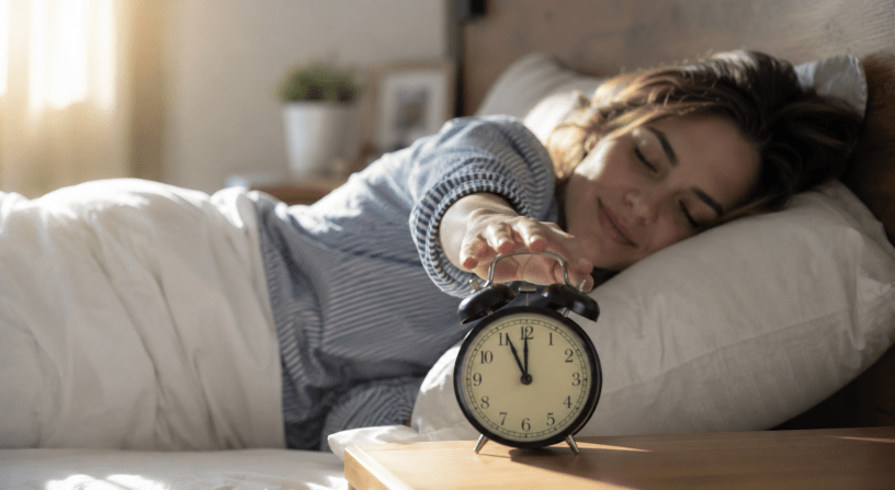 Persona che si sveglia serenamente pochi istanti prima che la sveglia suoni, in una luminosa camera da letto, simbolo del funzionamento dell'orologio biologico e dei ritmi circadiani.