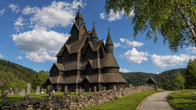 Chiesa medievale in legno di Heddal a Notodden, circondata dal verde e da un antico cimitero sotto il cielo della Norvegia.