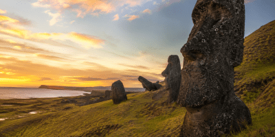 Veduta panoramica dell'Isola di Pasqua al tramonto con alcuni Moai in primo piano affacciati sull'oceano, simbolo del rapporto tra uomo, ambiente e sostenibilità. Immagine illustrativa realizzata con intelligenza artificiale.