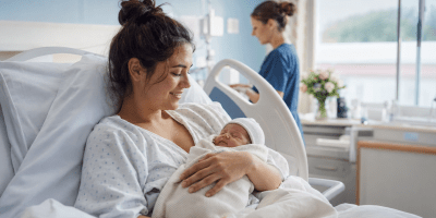 Giovane madre in ospedale tiene in braccio il neonato dopo un ictus in gravidanza.