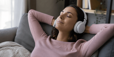 Una persona rilassata ascolta musica con cuffie in un ambiente domestico, simbolo degli effetti benefici della musica sul benessere psicofisico e sulla percezione del dolore.