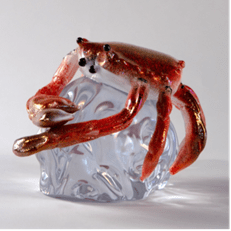 A glass sculpture of a red crab resting on a translucent blue base.