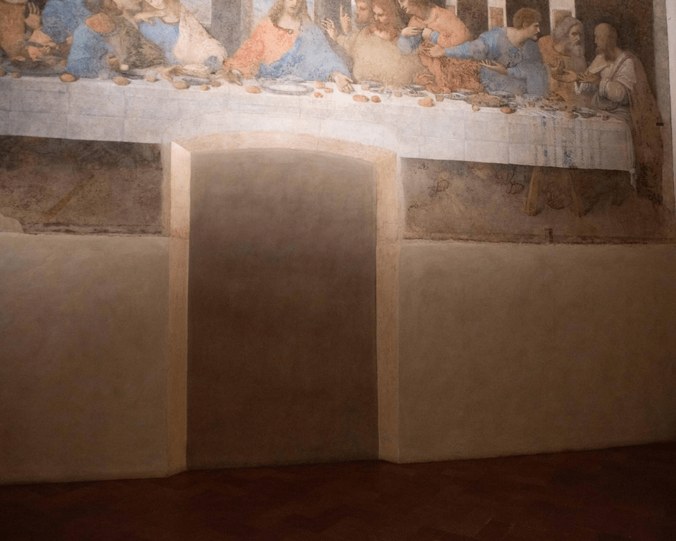 Interior view of a room featuring a section of The Last Supper mural on the wall, with a plain door frame visible.