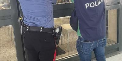 Un Carabiniere e un agente di Polizia affiggono il provvedimento di sospensione della licenza all’ingresso di un locale.