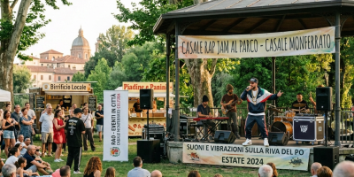 Outdoor concert with crowd, band, and banners reading Rao Music al Parco, Casale Monferrato; Suoni e Vibrazioni sulla Riva del Po, Estate 2024