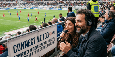Commentators provide audio description beside a sign reading "CONNECT ME TOO" in an Italian football stadium