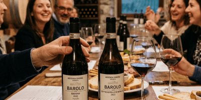 Two Barolo DOCG 2022 bottles labeled Ravera and Sottocastello di Novello beside wine glasses and food