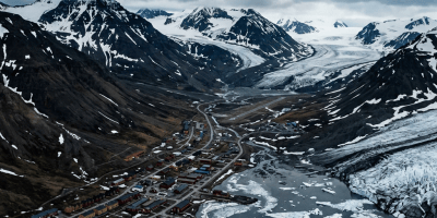 Remote settlement beside a glacier-fed fjord and snow-covered mountains
